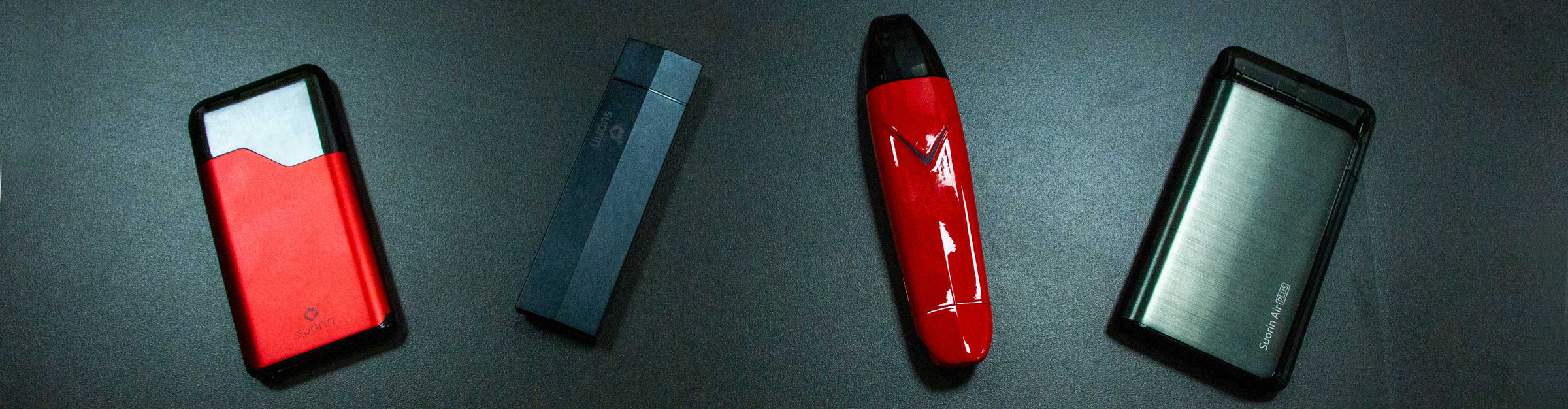 Wholesale Suorin Products Suorin Air, Edge, Vagon, and Air Plus lined up in a row on black table in florescent lighting